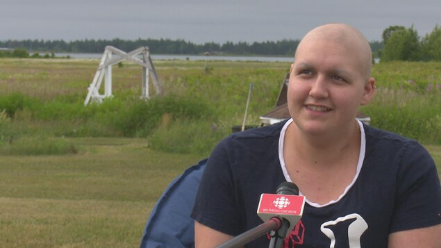 Un micro de Radio-Canada est tendu vers Noémie qui répond à une question alors qu'elle se trouve dans un champ.