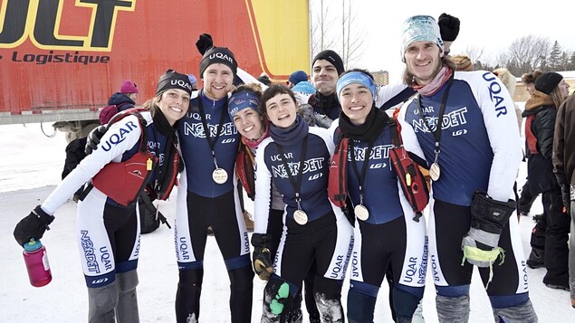 Cinq athlètes, hommes et femmes, montrent leur médaille d'or.