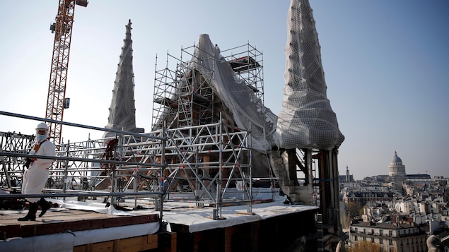 Le toit de Notre-Dame en chantier de construction avec des échafaudages et des grillages de protection autour des tourelles. 