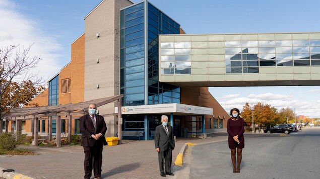 Trois administrateurs posent devant le centre de soins à deux mètres de distance, et en portant des masques.