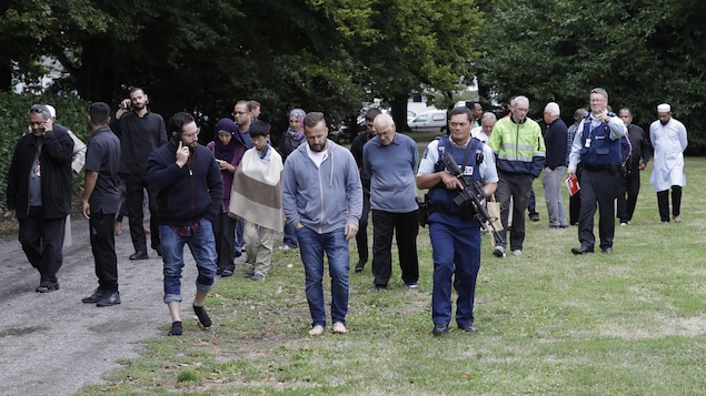 Une foule est escortée par des policiers.