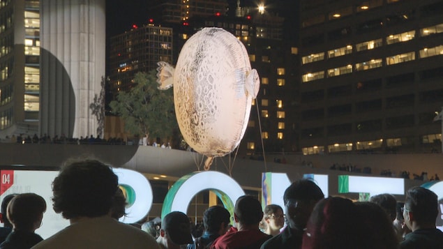 Une oeuvre qui flotte au-dessus des lettres géantes illuminées de Toronto.