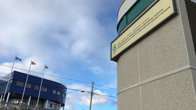 A side shot of the Nunavik Regional Board of Health and Social services building with a cloudy blue sky behind it. 