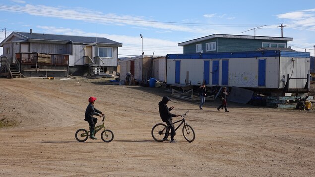 Des enfants font de la bicyclette dans une rue de Clyde River.