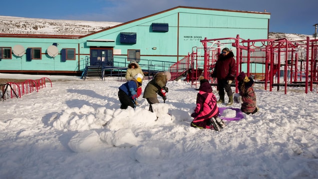 Des enfants construisent un igloo dans la neige devant l'école Nanook, près d'Iqaluit, le 4 novembre 2022.