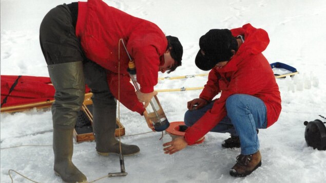 Deux étudiants prèlèvent des échantillons d'eau dans la glace, près d'Iqaluit, en avril 1998.