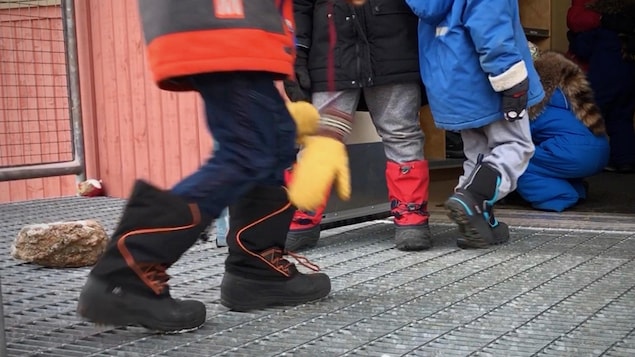 Des enfants habillés pour l'hiver entrent dans une école.