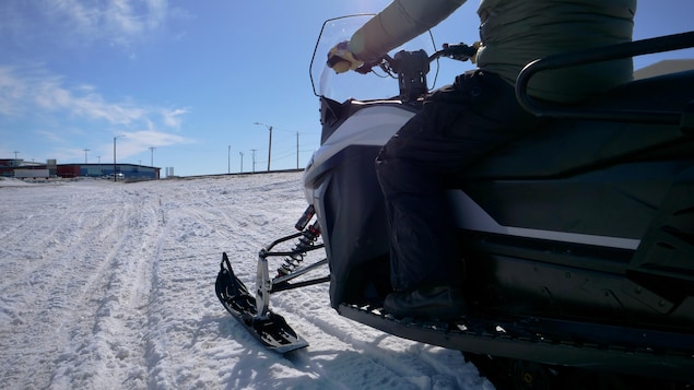 Un homme est assis sur une motoneige électrique et conduit dans un sentier enneigé, à Iqaluit, au Nunavut, le 16 avril 2024.