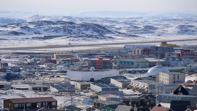 Des maisons d'Iqaluit avec des montagnes à demi enneigées à l'arrière-plan.