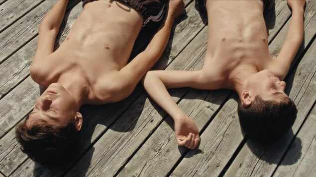 Deux garçons se bronzent au soleil sur un quai.