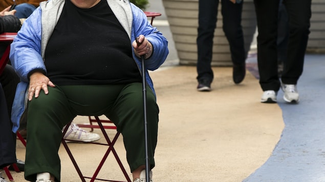 Une femme en surpoids assise sur une chaise à Times Square à New York.
