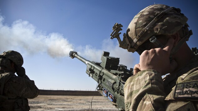 Un soldado se tapa las orejas mientras un obús abre fuego.