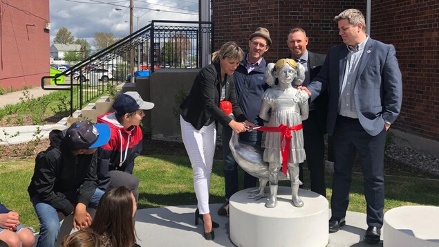 Des conseillers municipaux, la mairesse et l'artiste entourent la statue, devant les yeux amusés d'enfants.