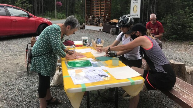 Trois femmes pratiquent le pochoir sur une table installée à l'accueil de la forêt récréative.