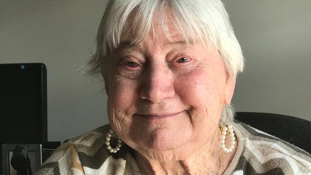 La dame porte un collier et des boucles d'oreilles avec des perles et mange par elle-même.