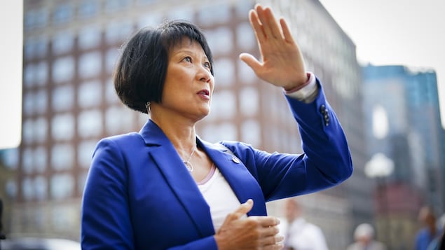 Vêtue d'un veston, Olivia Chow plie son bras gauche en l'air.