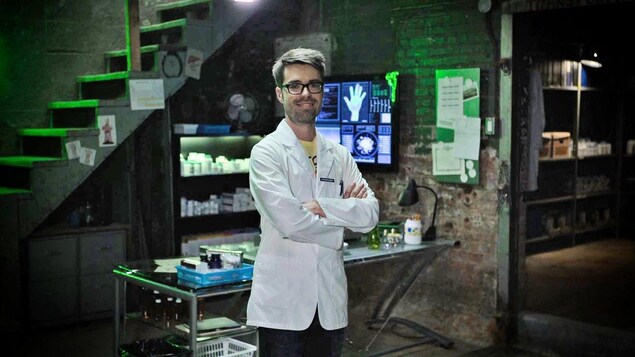 Olivier Bernard, alias Le Pharmachien, pose en blouse blanche dans le laboratoire de son émission Les aventures du Pharmachien.