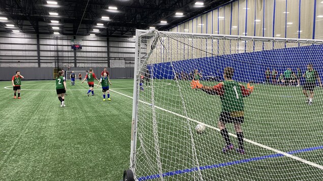 Des jeunes qui jouent au soccer sur un terrain intérieur.
