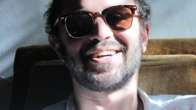 Portrait en couleur d'Olyvier Leroux-Picard, souriant, avec des lunettes de soleil.