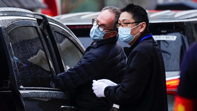 Les deux hommes entrent dans une voiture.