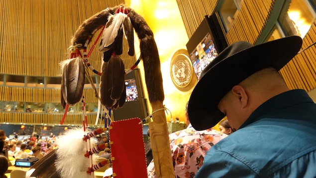Cheyenne Kitchikake tient un bâton recouvert de plumes dans la salle de l'ONU.