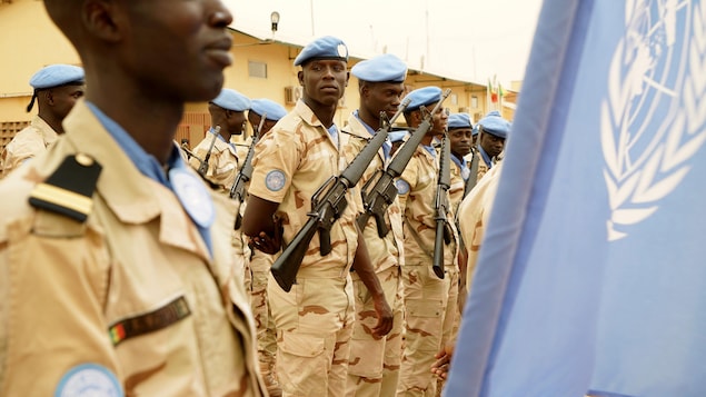 Des soldats portant le béret bleu de l'ONU en rang à l'extérieur d'une base militaire au Mali.