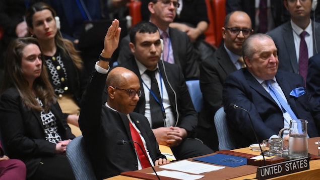 Un homme levant la main droite dans une réunion.