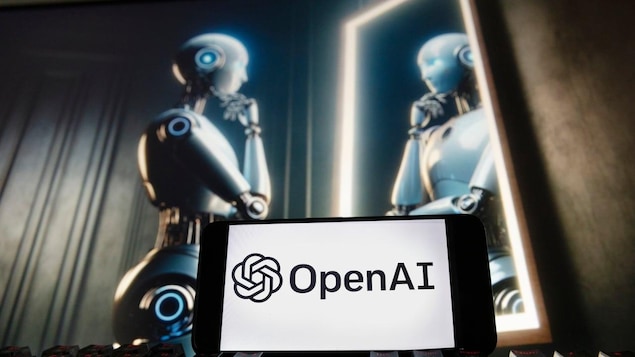 Un robot humanoide futurista mirando su reflejo en un espejo en una pantalla. Delante de la pantalla, un teclado y un celular con el logotipo de OpenAI.