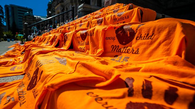 Nasa hagdan sa tapat ng building ang mga orange na t-shirt na nagsasabing every child matters. 