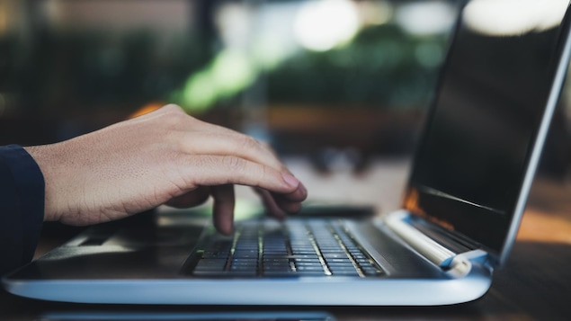 Une main d'homme sur le clavier d'un ordinateur portable.