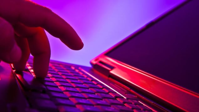 Un homme appuie sur les touches du clavier d'un ordinateur portable