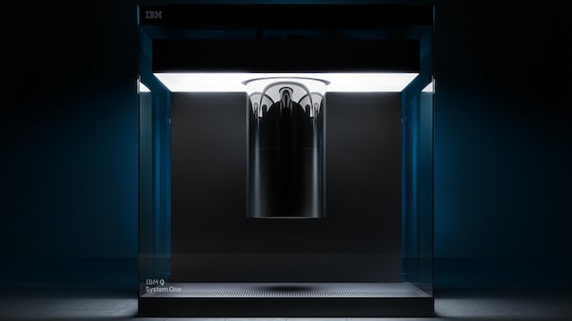 Une photo montrant l'ordinateur quantique Q System One d'IBM, un grand cube de verre contenant un cylindre chromé suspendu.