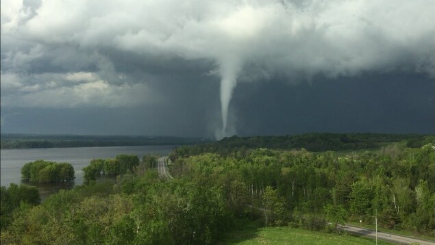 Une tornade près d'une rivière vue de loin.