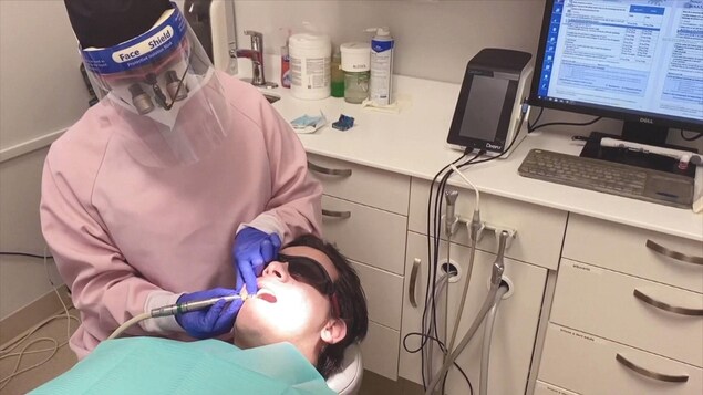 Une employée d'une clinique dentaire prend des photos des dents d'un patient.