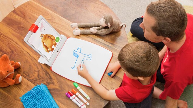 Un enfant dessine assisté d'un monstre virtuel qui le guide dans sa tâche. Un enfant dessine assisté d'un monstre virtuel qui le guide dans sa tâche.