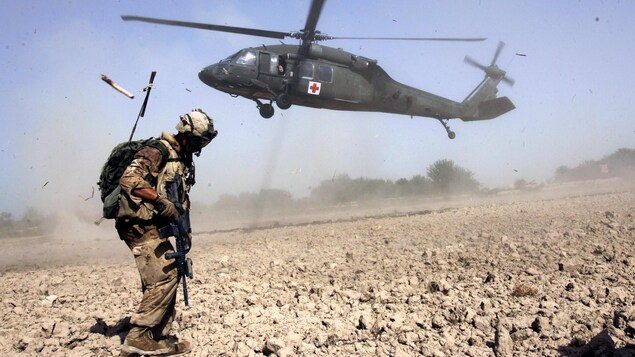 Un soldat canadien de l'OTAN attend l'hélicoptère qui est en train d’atterrir. Un soldat canadien de l'OTAN attend l'hélicoptère qui est en train d’atterrir.