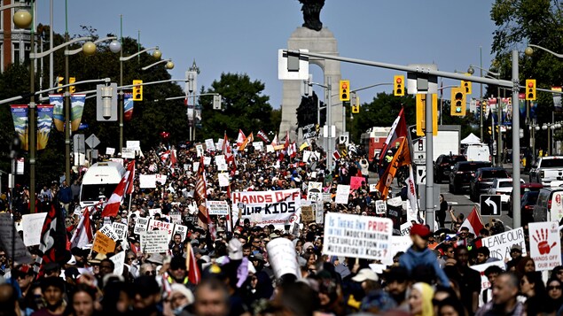 Une foule de manifestants, dont plusieurs brandissant des pancartes, dans une rue d'Ottawa.