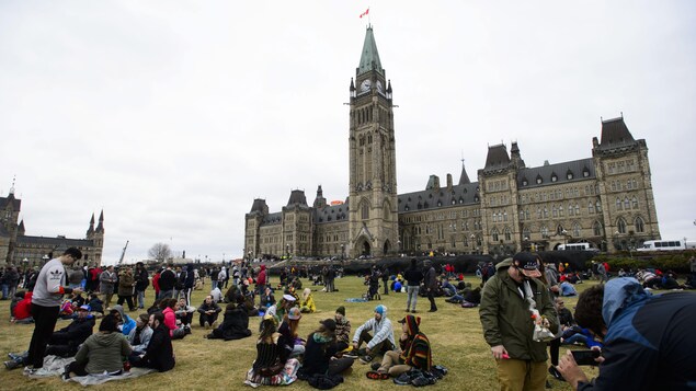 Des manifestants fument du cannabis sur la Colline du Parlement en participant au rassemblement annuel 4-20 à Ottawa, le samedi 20 avril 2019.
