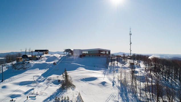 le chalet, tout en fenêtres, au sommet de la montagne enneigée