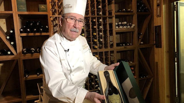 L'aubergiste montre une de ses nombreuses bouteilles rares rangée dans une boîte à vin.