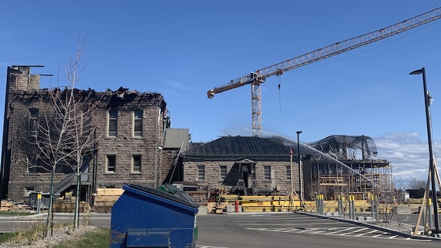 Un édifice ravagé par les flammes se dresse sous un ciel bleu.