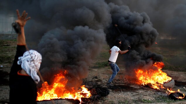 Des manifestants palestiniens lancent des roches sur des soldats israéliens près de la ville de Gaza. Des manifestants palestiniens lancent des roches sur des soldats israéliens près de la ville de Gaza.