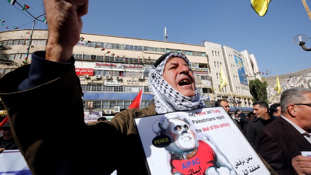 Un Palestinien tient une pancarte sur laquelle on peut lire : « Hé Pence. Dis à Trump que les Palestiniens rejettent l'entente du siècle ». Un Palestinien tient une pancarte sur laquelle on peut lire : « Hé Pence. Dis à Trump que les Palestiniens rejettent l'entente du siècle ».