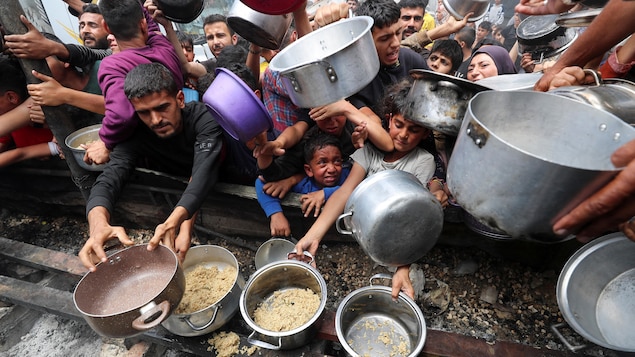 Des femmes, des hommes et des enfants tendent des sauts et des casseroles dans la cohue.