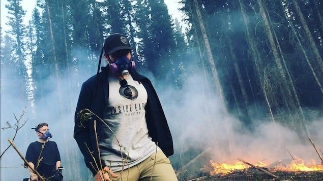 Deux hommes portant des masques pour se protéger de la fumée marchent sur le site d'un incendie. Deux hommes portant des masques pour se protéger de la fumée marchent sur le site d'un incendie.
