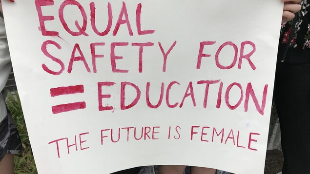 Deux filles tiennent une pancarte qui dit en anglais « pour une éducation et sécurité égales. Le futur est féminin ». Deux filles tiennent une pancarte qui dit en anglais « pour une éducation et sécurité égales. Le futur est féminin ».