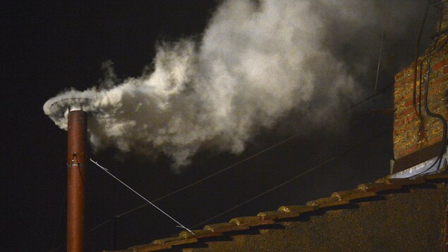La fumée s'échappe en pleine nuit d'une mince cheminée rouge. La fumée s'échappe en pleine nuit d'une mince cheminée rouge.
