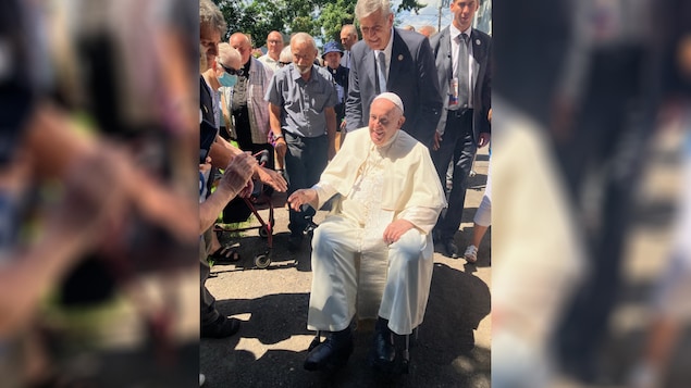 Assis dans son fauteuil roulant, le pape François serre des mains en souriant