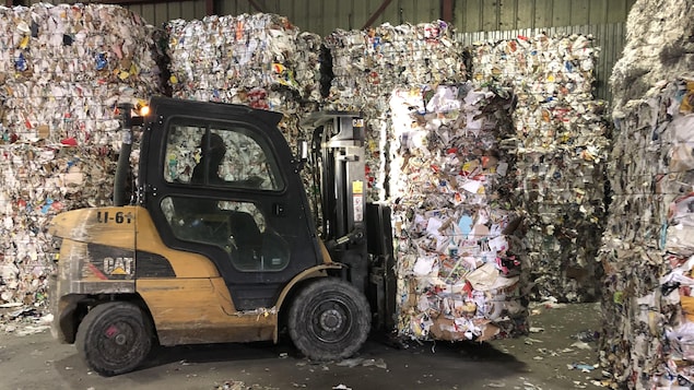 Une machine transporte un ballot de papier.