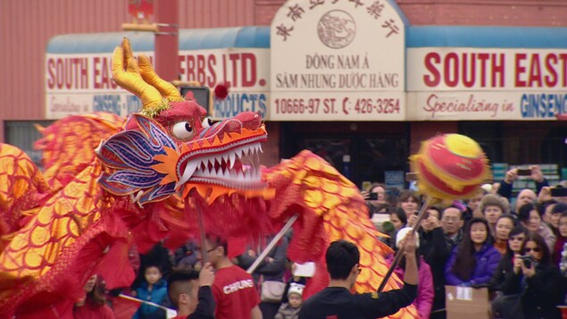 Un dragon chinois en tissus est promené dans la rue devant des spectateurs. Un dragon chinois en tissus est promené dans la rue devant des spectateurs.